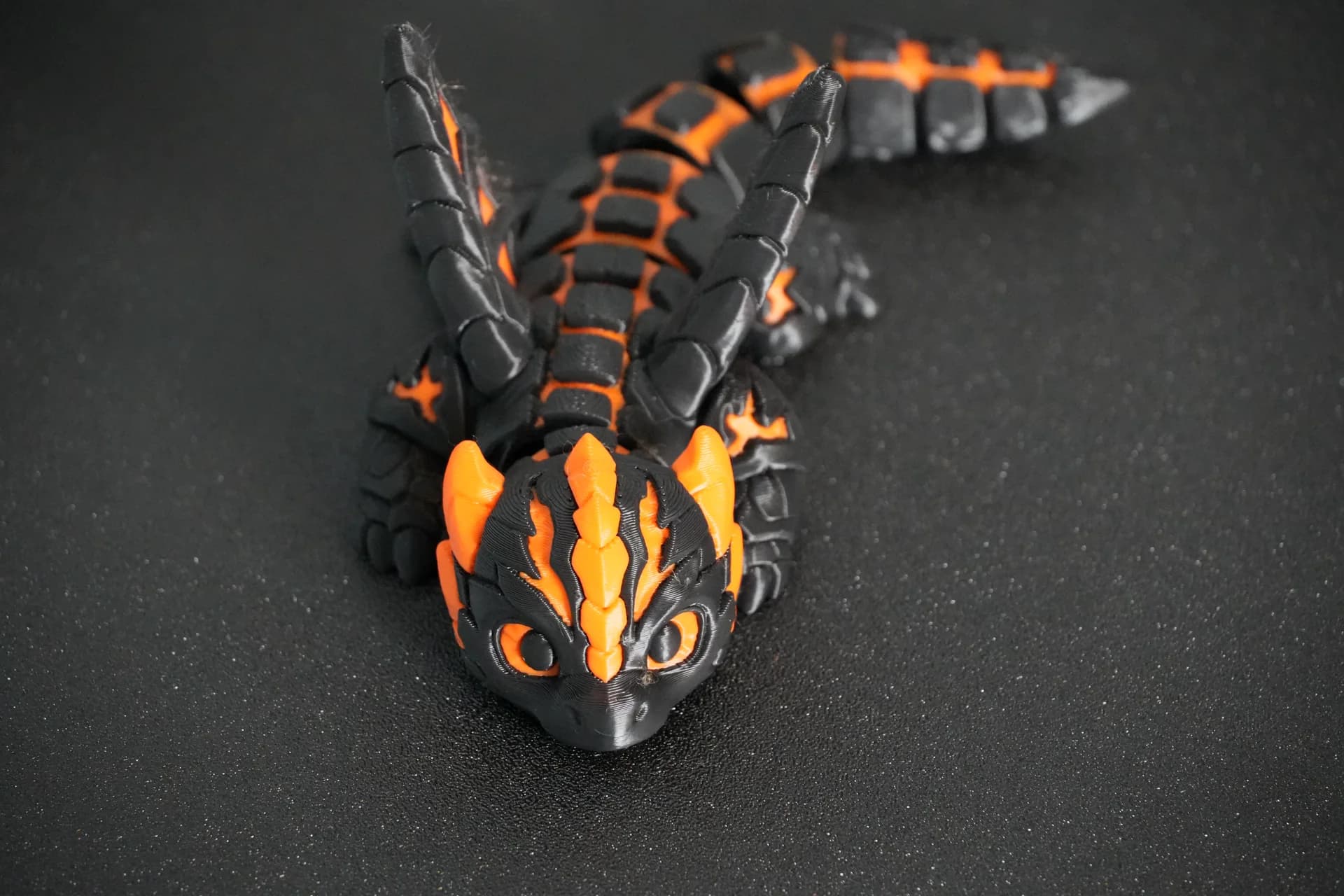 Black and orange articulated dragon printed on an Anycubic Kobra X