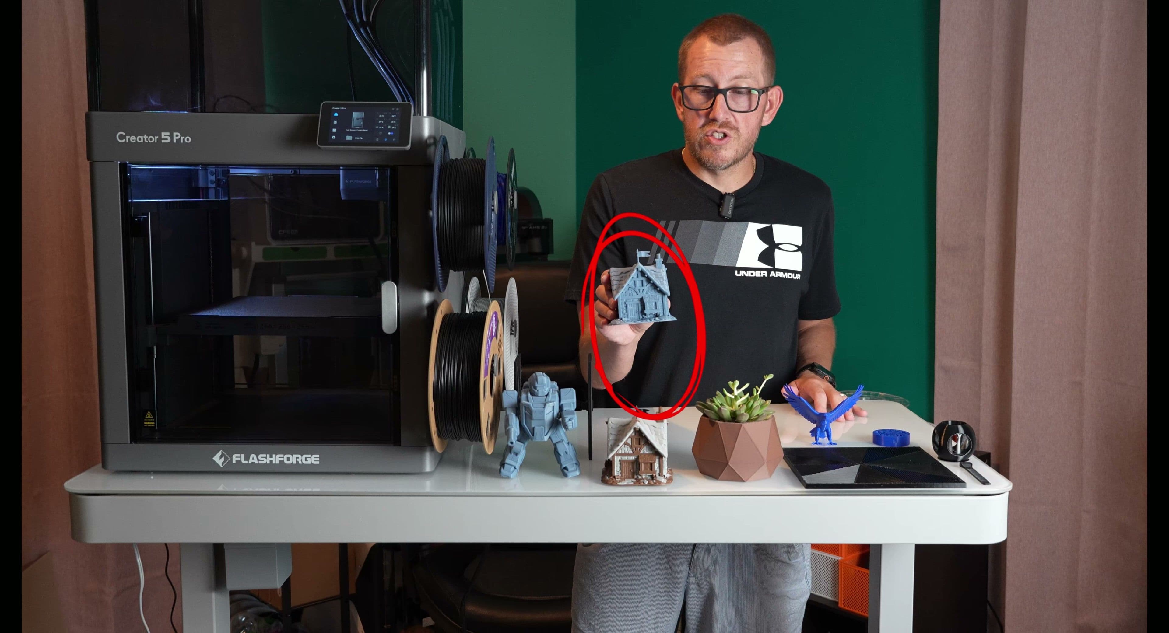 Rob holding a printed part beside a Flashforge Creator 5 Pro printer